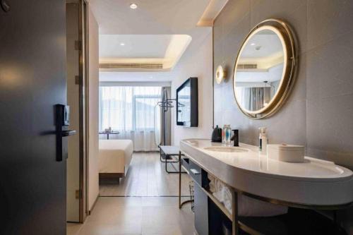 Un baño con lavabo y espejo y un dormitorio. en Atour X Hotel Jinan Jingshi Road Provincial Sports Center, en Jinan