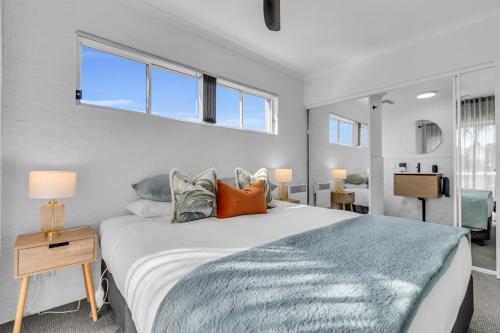 a bedroom with a large white bed and windows at The Palms Apartments in Merimbula