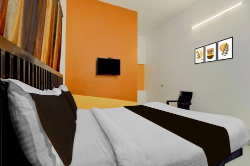 a bedroom with a bed and a tv on the wall at Super Hotel O Auroville Bird Sanctuary Chennai Formerly Vanam Resort in Puducherry