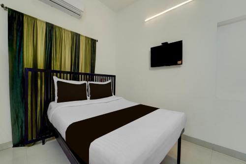 a bedroom with a bed and a tv on the wall at Super Hotel O Auroville Bird Sanctuary Chennai Formerly Vanam Resort in Puducherry