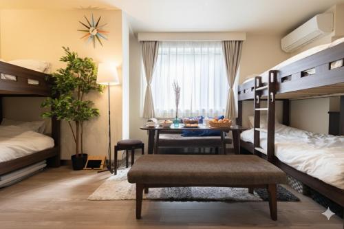 a bedroom with two bunk beds and a table and a desk at “1ST ROOM” 内装デザイナー監修！30㎡ 最大6名 経堂駅から徒歩5分 築浅 良質な暮らしを in Tokyo