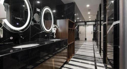 a black bathroom with two sinks and mirrors at Shenzhen Nan Fei Yuan Hotel in Shenzhen