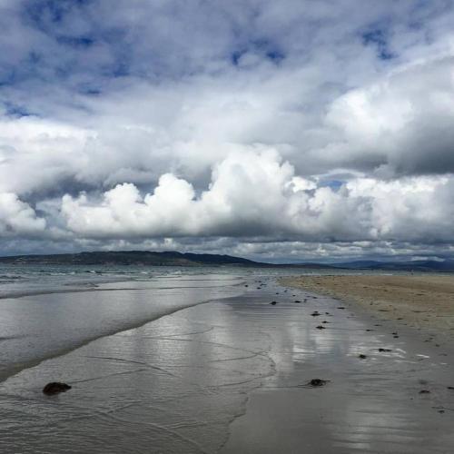 a beach with footprints in the sand and a cloudy sky at Brook Lodge in Glenties
