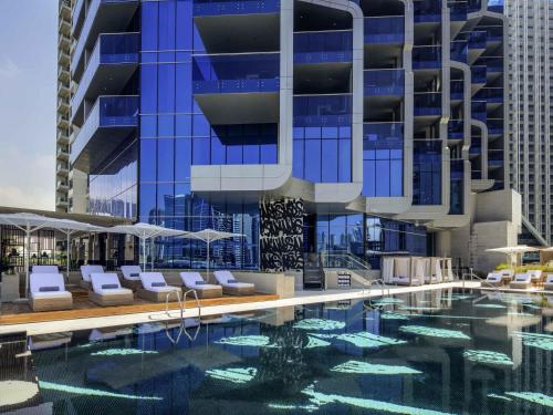a hotel swimming pool with chairs and a building at Hyde Hotel Dubai in Dubai