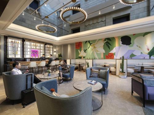 um lobby com pessoas sentadas em cadeiras e mesas em Mercure Shanghai Jinqiao em Xangai