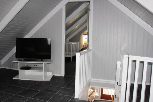 a living room with a television and a staircase at Brekkugisting Villa in Blaskogabyggd