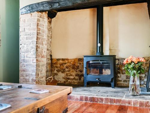 ein Kamin in einem Raum mit einem Tisch und Blumen in der Unterkunft Cider Cottage in Fordingbridge