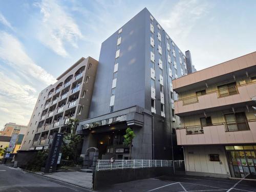 a tall building on a street next to a parking lot at Hotel Route-Inn Kitamatsudo Ekimae in Matsudo