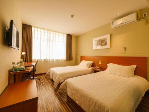 a hotel room with two beds and a desk at Jinjiang Inn Style Shenyang The Palace Huaiyuan Gate in Shenyang