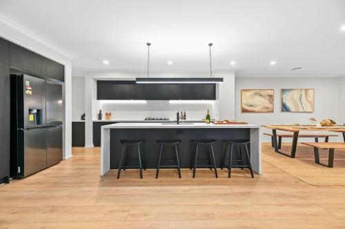 a kitchen with a large island with bar stools at Breach House Rhyll in Rhyll