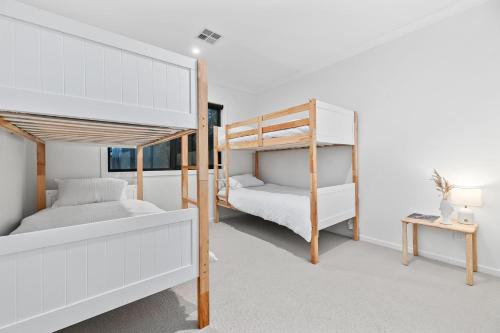 a bedroom with two bunk beds and a desk at Breach House Rhyll in Rhyll