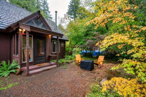 Una pequeña casa con dos sillas y un porche. en Rhododendron Cabin Near Mt Hood Adventures, en Brightwood