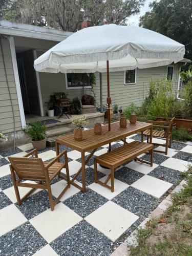eine Terrasse mit einem Tisch, 2 Stühlen und einem Sonnenschirm in der Unterkunft Cozy Guest house near FSU Trails and the airport in Tallahassee