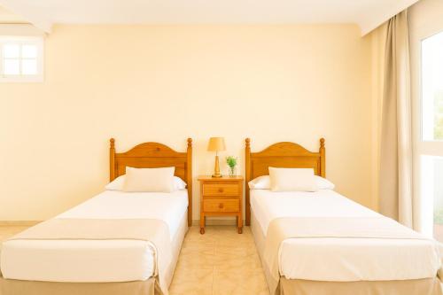 two beds in a room with white walls at Be five Playa La Arena in Puerto de Santiago