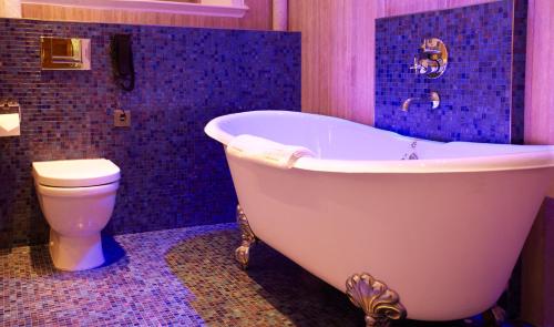 a bathroom with a white tub and a toilet at South Lodge in Lower Beeding