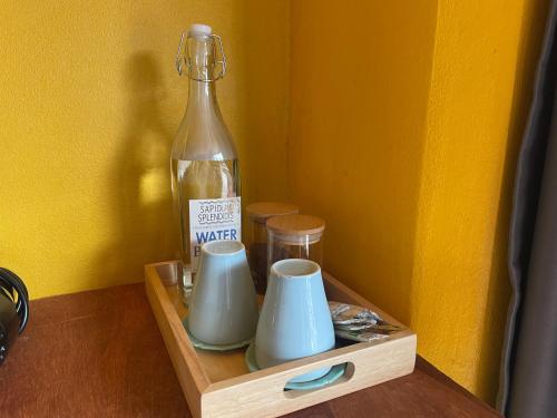 Una botella de agua y dos tazas en un estante de madera. en Over the Moon hostel, en Ban Houayxay