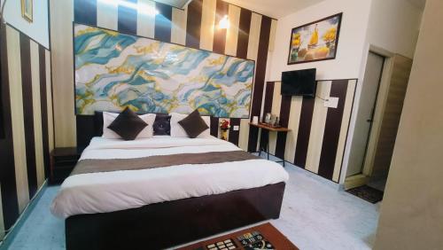 a bedroom with a large bed with a painting on the wall at Hotel Mannat - Near Thyagaraj Sports Complex in New Delhi