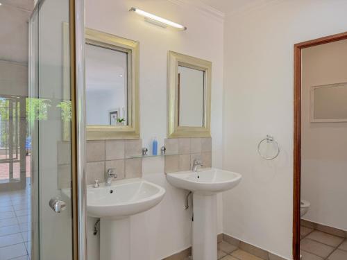 a bathroom with two sinks and a glass shower at Amoris Guesthouse on Orion in Pretoria
