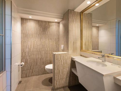 a bathroom with a sink and a toilet and a mirror at Mövenpick Hotel Windhoek in Windhoek