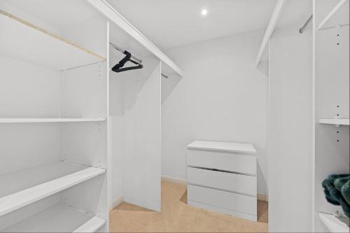 a white walk in closet with white cabinets at Spacious 3-Bedroom Apartment + Lifestyle Amenities in Downer