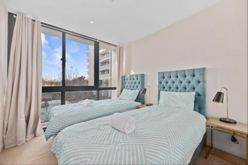 a bedroom with two beds and a large window at Spacious 3-Bedroom Apartment + Lifestyle Amenities in Downer