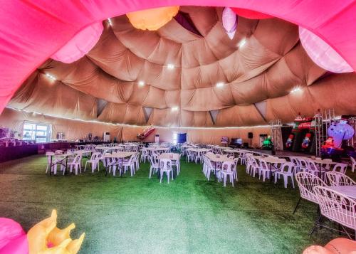 ein Raum mit weißen Tischen und Stühlen in einem Zelt in der Unterkunft FarmKO Glamping in Dolores