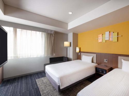 a hotel room with two beds and a television at ibis Styles Kyoto Shijo in Kyoto