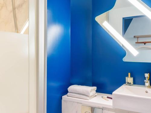 a bathroom with blue walls and a white sink at IBIS BUDGET CAPAO Bonito in Capão Bonito