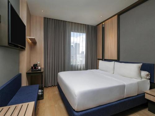 a bedroom with a large white bed and a window at ibis Surabaya Tidar in Surabaya