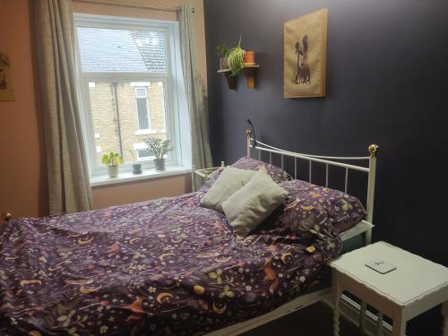 a bed with a purple comforter and a window at Bishop Auckland B and B in Bishop Auckland