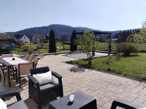 eine Terrasse mit einem Tisch, Stühlen und einem Feld in der Unterkunft ForRest Spa Apartment - Private Jacuzzi & Sauna in Ravna Gora