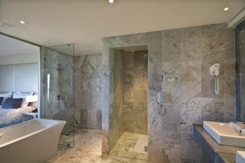 a bathroom with a tub and a sink and a shower at Royal Thalassa Monastir in Monastir