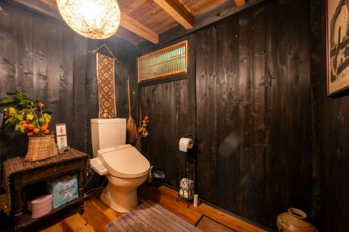 a bathroom with a toilet and a wooden wall at 木古里ゲストハウス Kicoli guesthouse in Chizu