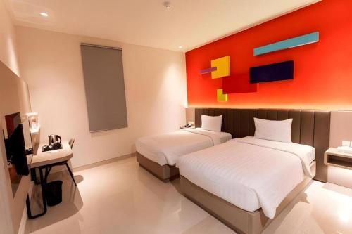 a hotel room with two beds and a painting on the wall at Zoom Dharmahusada Hotel in Surabaya