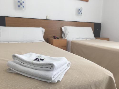 two beds with white towels and a robe on them at Hostal R. Lido in Madrid