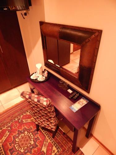 a wooden table with a chair and a mirror at Border Close Guesthouse in Upington