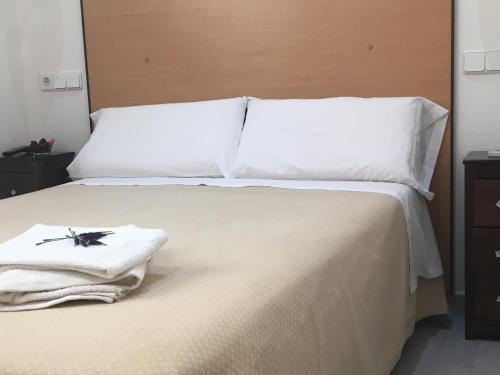 a bed with white sheets and a towel on it at Hostal R. Lido in Madrid