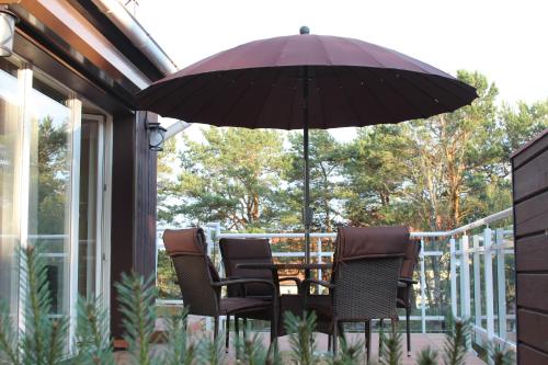 a table and chairs under an umbrella on a porch at Holiday Terrace Nida in Nida