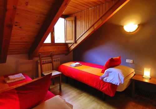 a bedroom with a red bed in a attic at Apartament Boliera in Espot