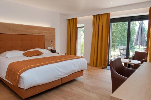 a bedroom with a bed and a desk with a chair at Hotel Le Charme de la Semois in Alle