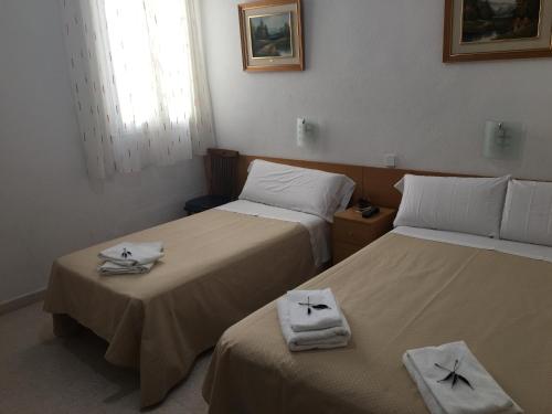 Dos camas en una habitación con toallas. en Hostal R. Lido, en Madrid