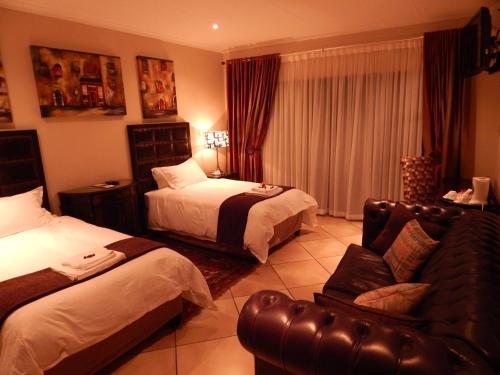 a hotel room with two beds and a couch at Border Close Guesthouse in Upington