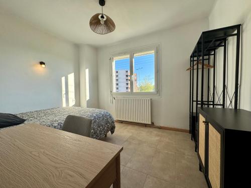 a bedroom with a bed and a table and a window at Le Cosy Cévenol - Jardin et terrasse in Alès