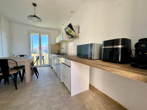a kitchen with a counter with a table and a microwave at Le Cosy Cévenol - Jardin et terrasse in Alès