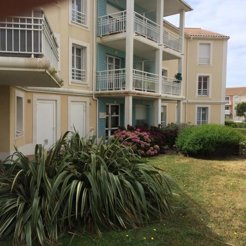 un edificio de apartamentos con balcones y plantas en un patio en Maupin Stéphane, en Saint Gilles Croix de vie