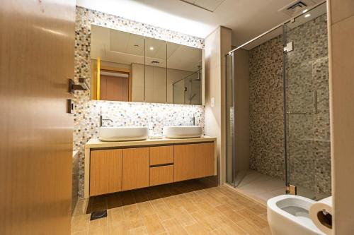 a bathroom with two sinks and a shower at Luxury 2BR Golf View 85" TV Yas Bay in Abu Dhabi