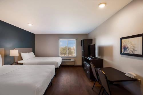 Una habitación de hotel con dos camas, un escritorio y una ventana. en WoodSpring Suites Orlando West - Clermont, en Clermont