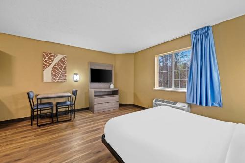 a hotel room with a bed and a table and chairs at Suburban Studios Charlotte - Executive Park in Charlotte
