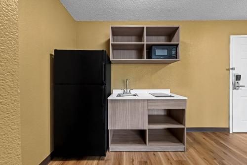 La cuisine est équipée d'un évier et d'un réfrigérateur noir. dans l'établissement Suburban Studios Charlotte - Executive Park, à Charlotte