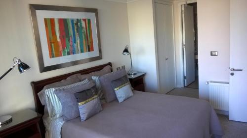 Un dormitorio con una cama con almohadas y una pintura en Apartamento Boutique Viña del Mar, en Viña del Mar